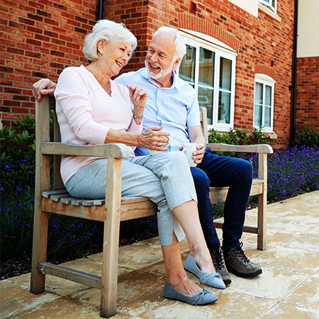 Group of seniors outdoors conversing with care provider